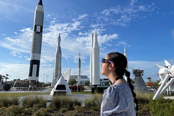 Woman looking up at the Sun with eclipse glasses standing in Rocket Garden