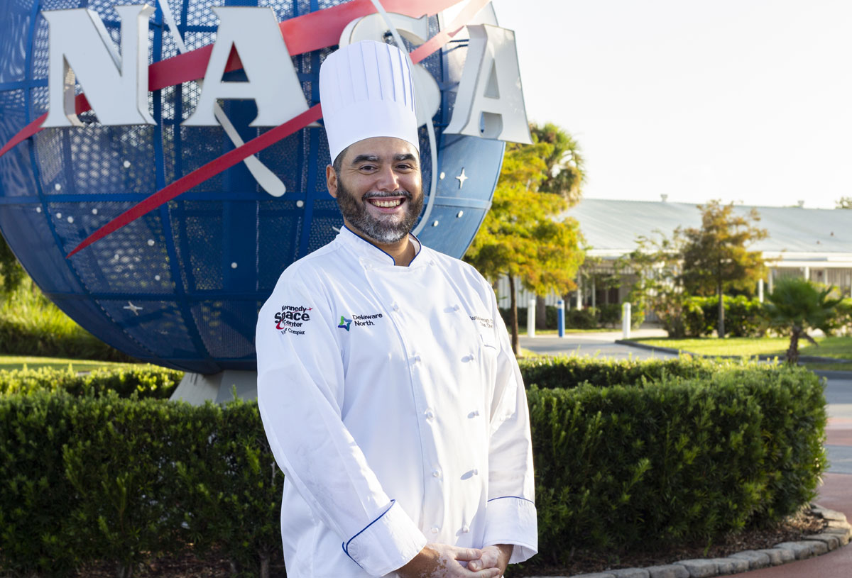 Sous Chef Israel "Izzy" Arroyo, CSC standing in front of NASA globe at Kennedy Space Center