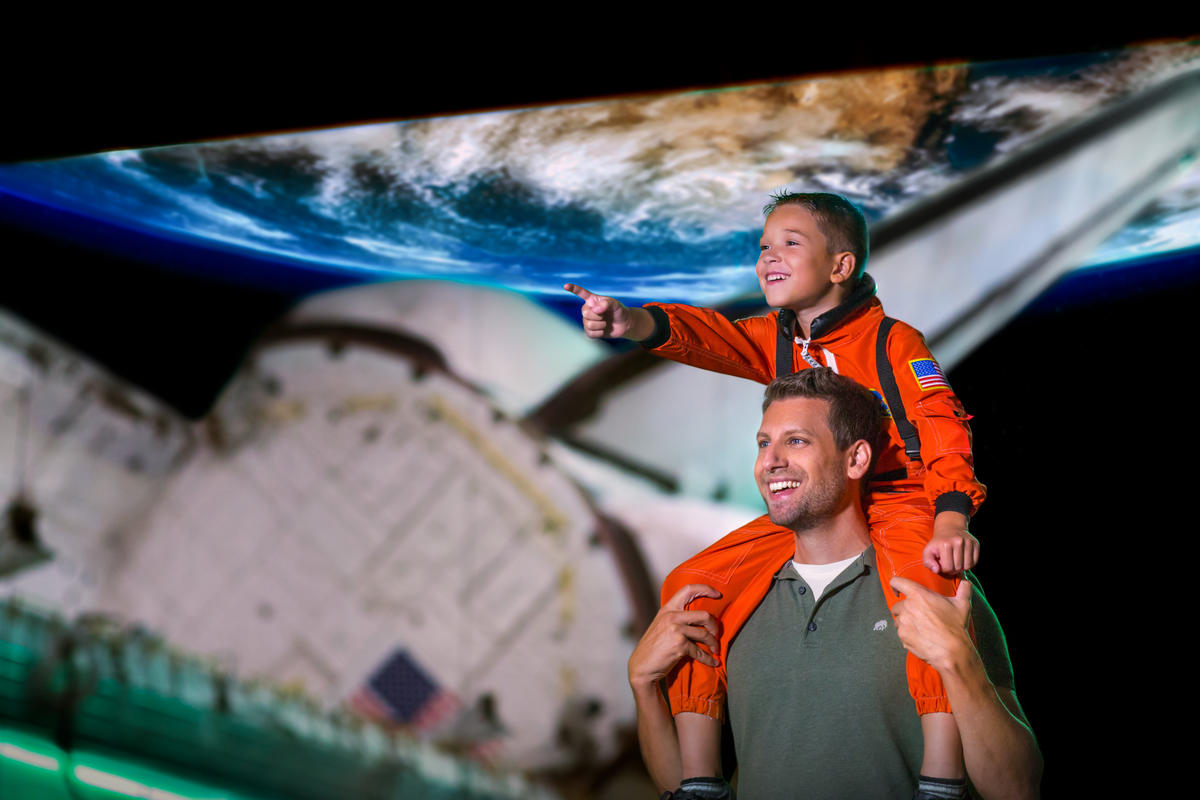 Father with son on his shoulders touring Space Shuttle Atlantis.