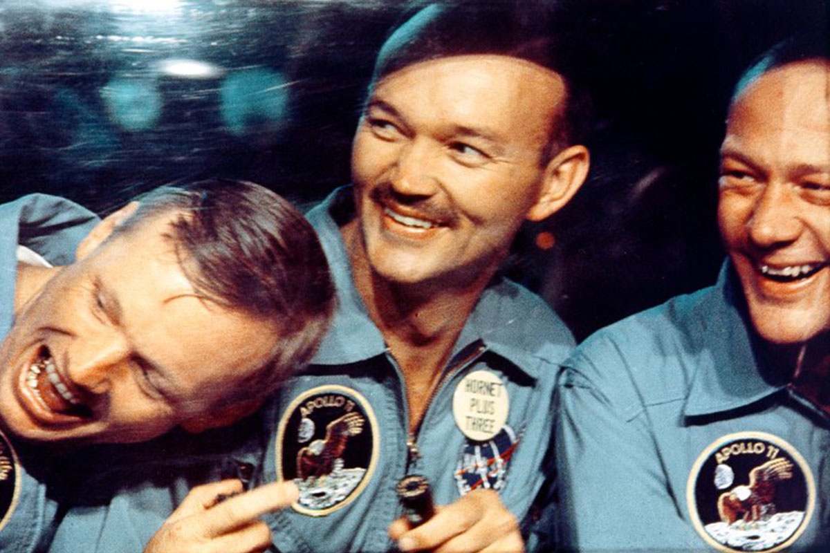 Apollo 11 astronauts Neil Armstrong, Mike Collins and Buzz Aldrin joke around as they peer out the window of an isolation chamber.