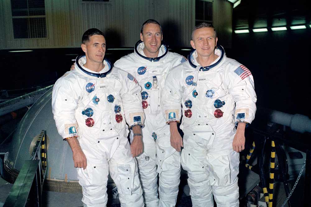 The prime crew of the Apollo 8 lunar orbit mission stands beside the gondola in Building 29 after training. Astronauts left to right are William Anders, James Lovell and Frank Borman.