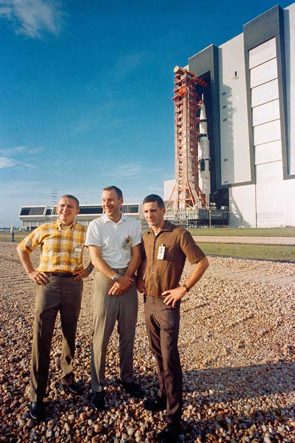 The Apollo 8 prime crew stands in foreground as the Apollo (Spacecraft 103/Saturn 503) space vehicle leaves the Kennedy Space Center's Vehicle Assembly Building on way to Pad A, Launch Complex 39. 