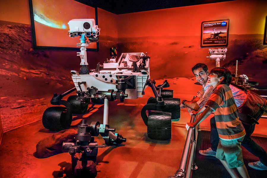 Father and son stare in awe at models of the Mars rovers.