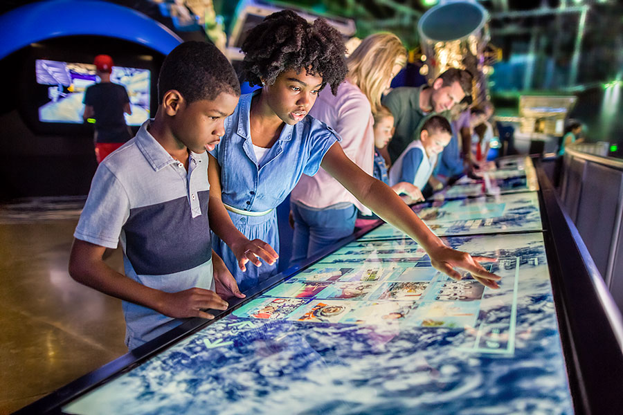 Children interacting with touch panels in the Space Shuttle Atlantis exhibit.