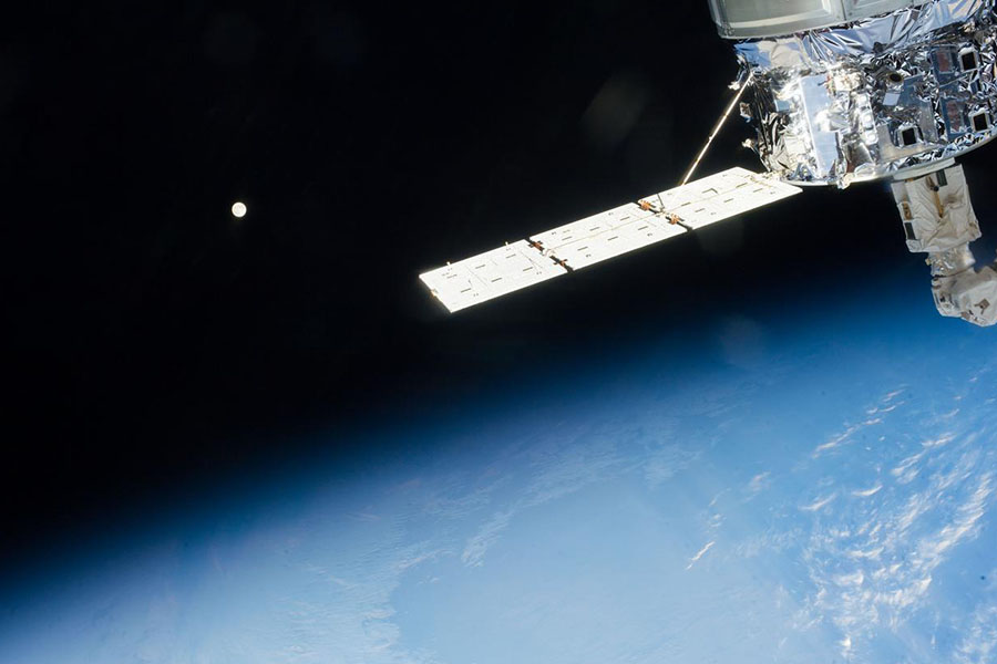 Distant view of the Moon over Earth limb taken by the Expedition 37 crew aboard the International Space Station (ISS). An ISS solar array is also visible.