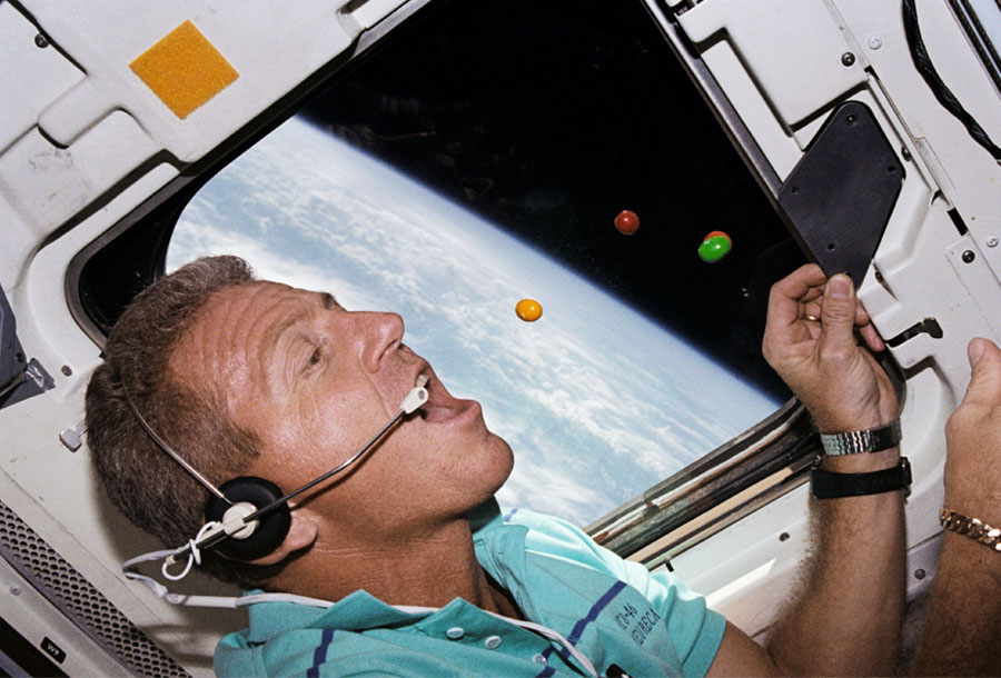Astronauta e comandante da STS-46, Loren J. Shriver, comendo bombons de chocolate flutuantes a bordo do ônibus espacial Atlantis (31 de julho a 8 de agosto de 1992)