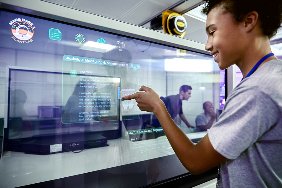 Estudante acompanha o crescimento de plantas em uma tela no ATX Center.