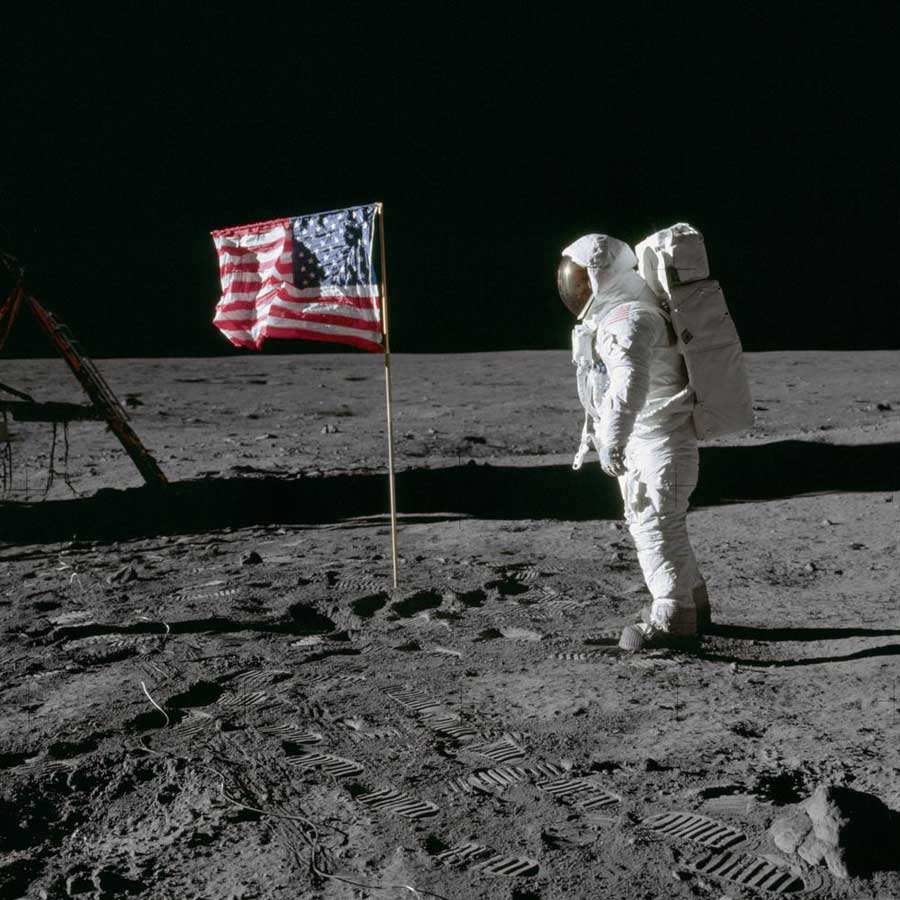 O astronauta Edwin E. Aldrin Jr., piloto do módulo lunar da primeira missão de pouso lunar, posa para uma fotografia ao lado da bandeira dos Estados Unidos hasteada durante uma atividade extraveicular (EVA) da Apollo 11 na superfície lunar.