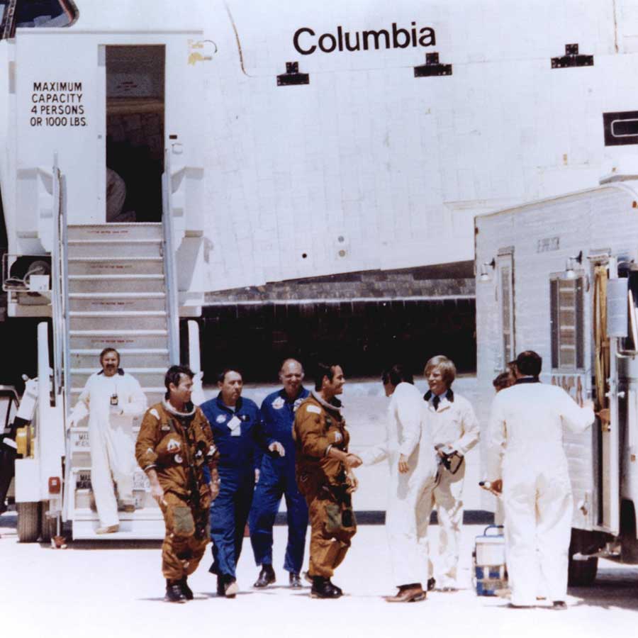 Os astronautas do ônibus espacial John Young e Robert Crippen (em trajes espaciais castanhos) são cumprimentados por membros da equipe de solo momentos depois de descerem do ônibus Columbia após seu primeiro pouso na Base Aérea de Edwards, Califórnia. Young e Crippen haviam pilotado o Columbia em sua primeira missão espacial orbital, de 12 a 14 de abril de 1981.