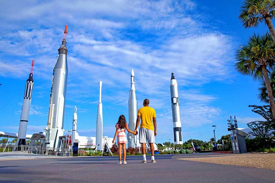 Pai e filha olham com admiração para o jardim de foguetes no Kennedy Space Center VIsitor Complex.