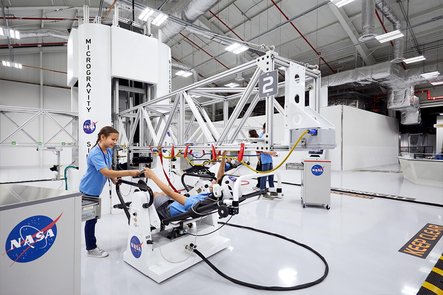 Os alunos sentam-se em cadeiras de microgravidade para experimentar como seria uma caminhada espacial na Estação Espacial Internacional.